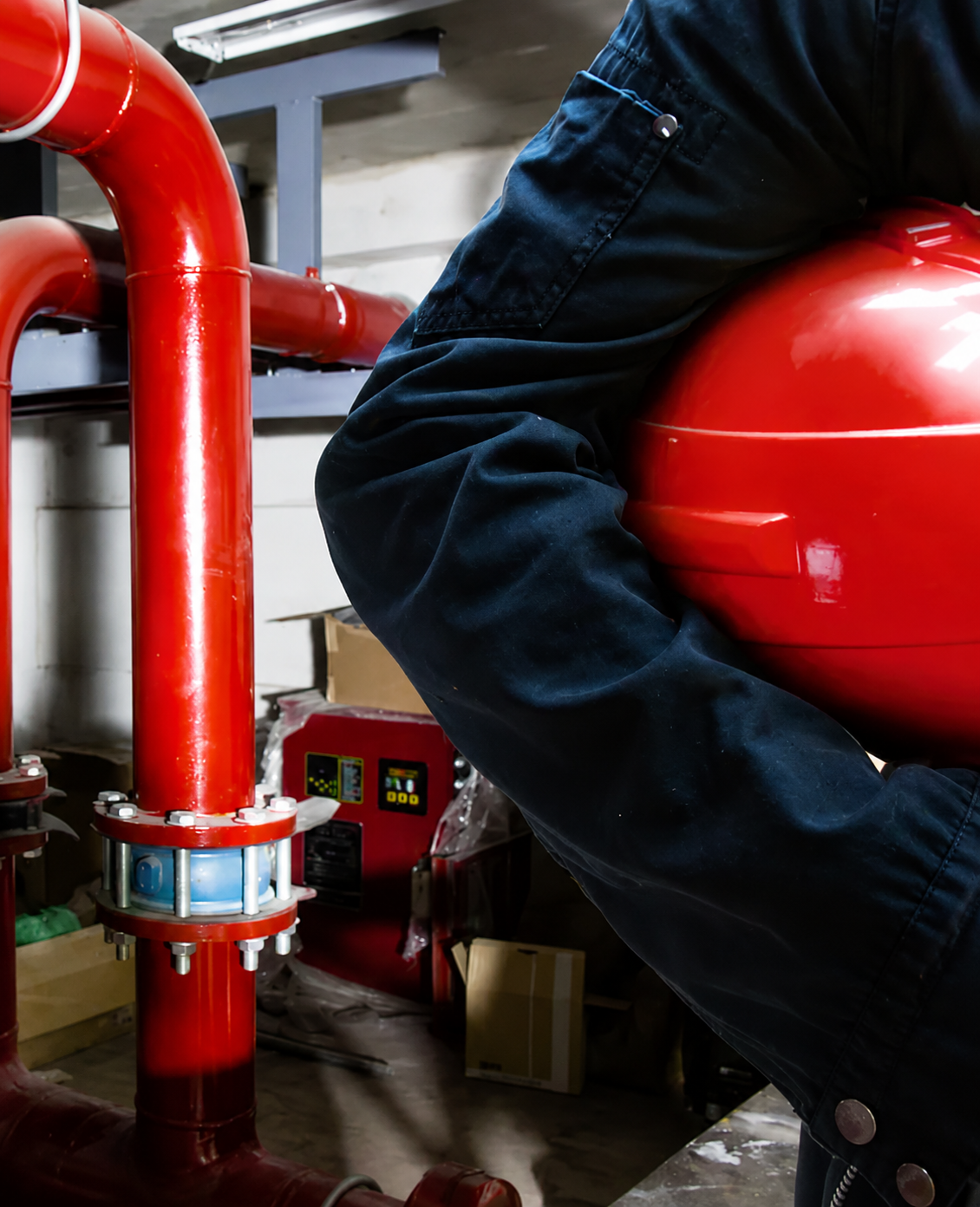 Fachkraft arbeitet an Brandschutztechnik und roten Rohrleitungen